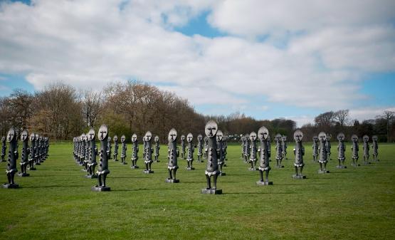 Dozens of identical statues standing in a field