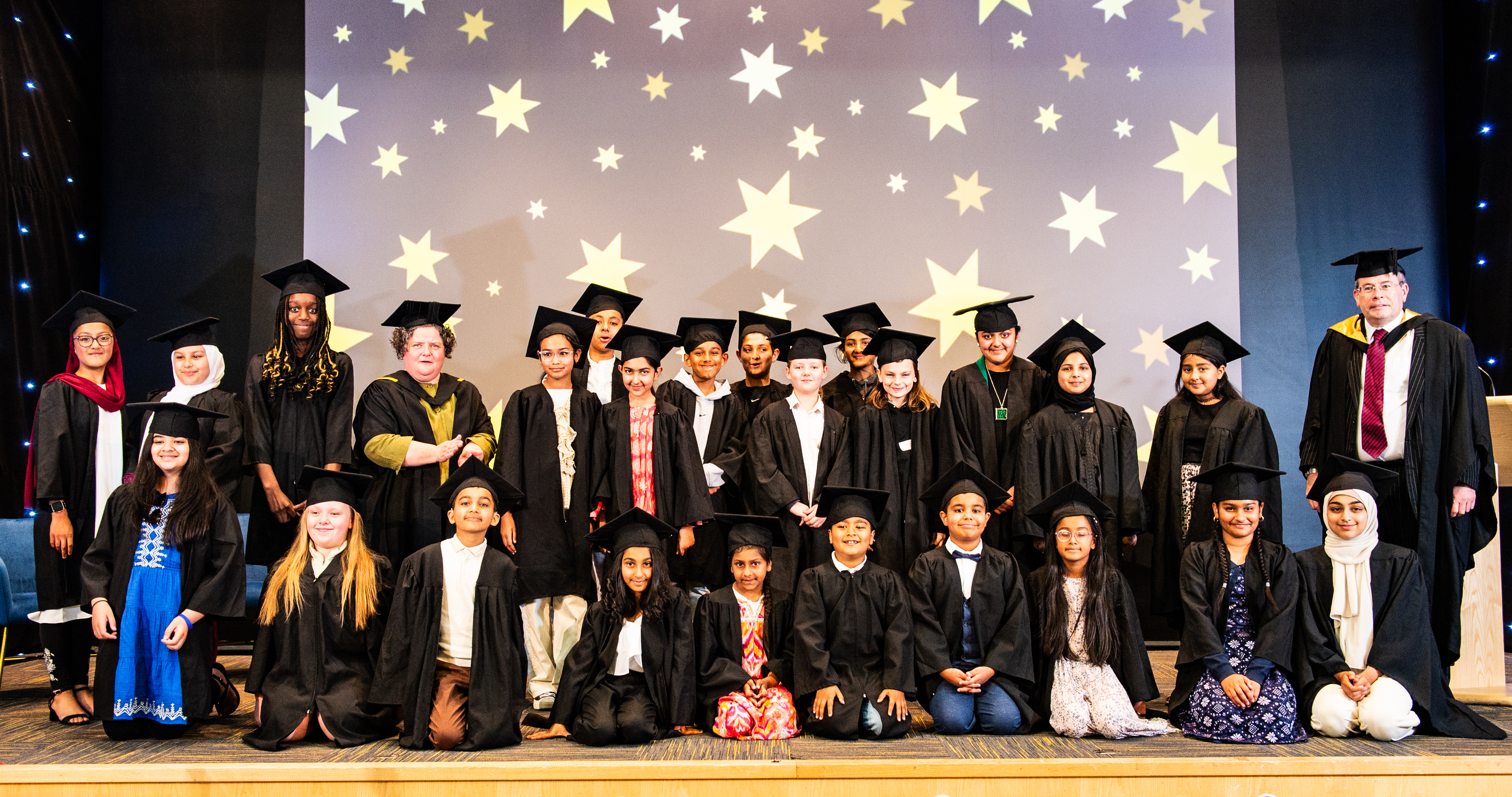Children in graduation robes on a stage