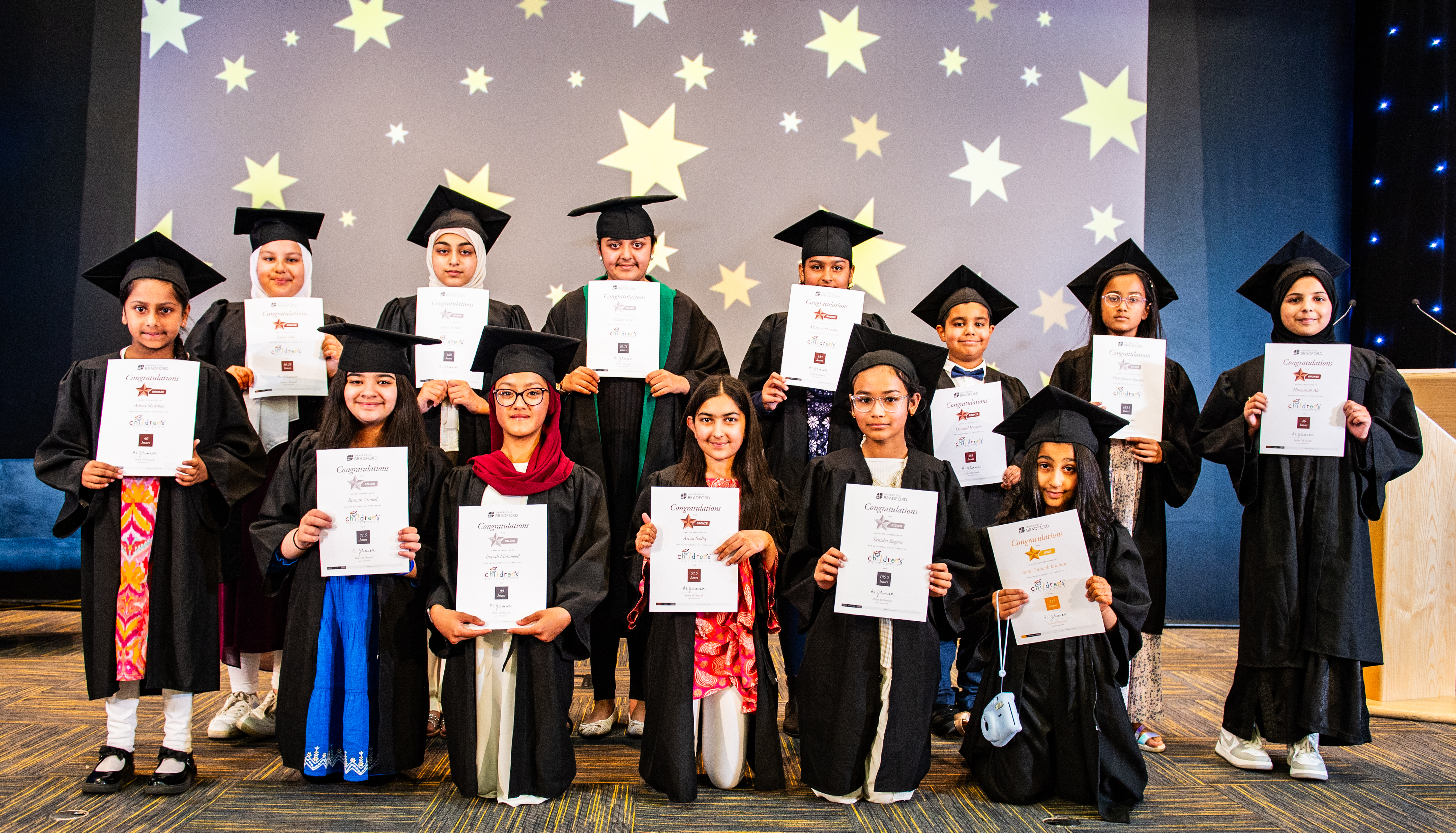Children in graduation robes with certificates