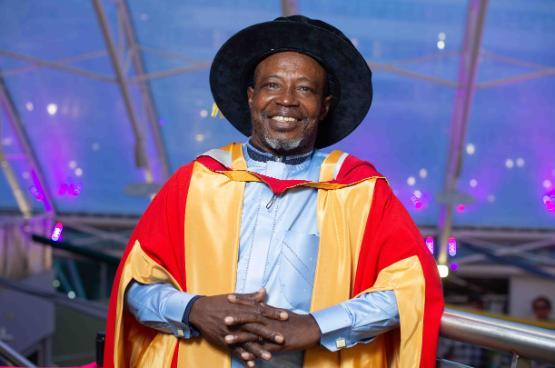 Honorary graduate in cap and gown smiles for camera