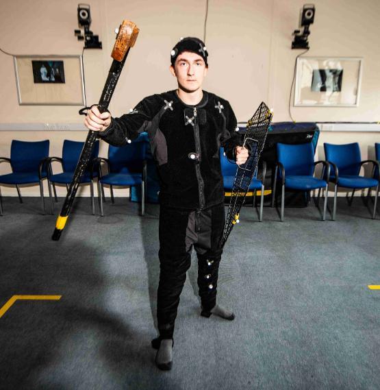 Student wears motion capture suit holding a toy weapon