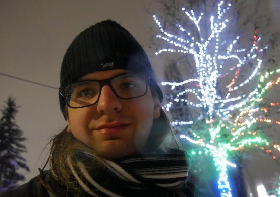 Student looking into camera with festive lights in tree behind