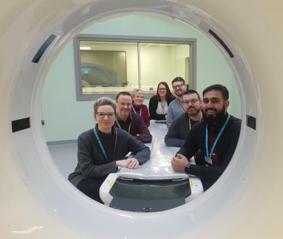 Staff from University look through the gap in a CT scanner