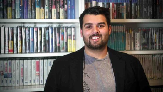 Alumni student stands in front of shelves filled with video games