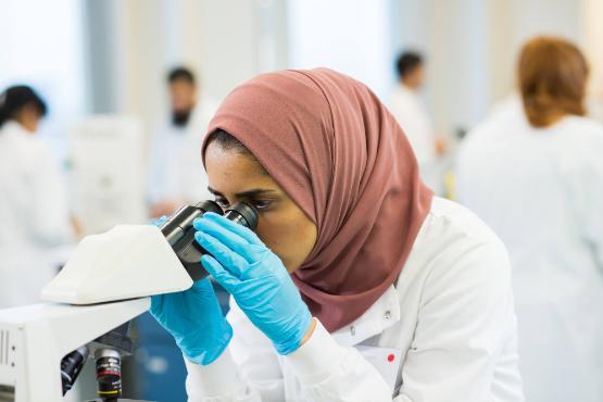 female student looks through a microscope