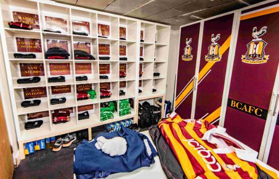 Football club shirts and tracksuit tops in locker spaces in room