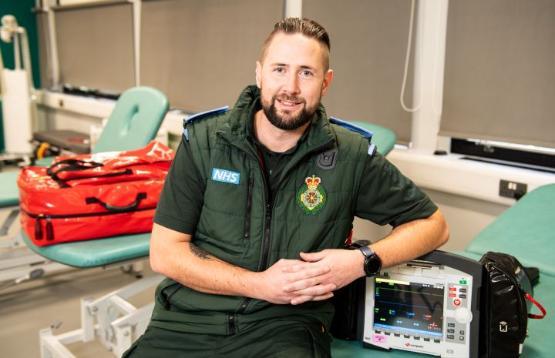 Student in paramedic uniform sat down by medical equipment
