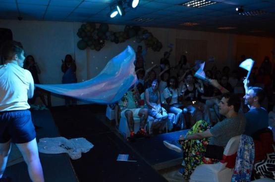 A performer on stage during a show holding a bed sheet out towards an audience
