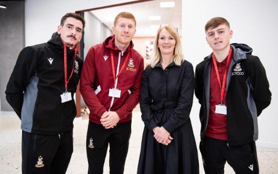 Three football players wearing tracksuits with University's Vice-Chancellor