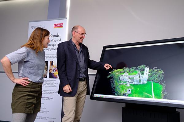 Prof Chris Gaffney pointing to a virtual 3D model of a building on a large screen