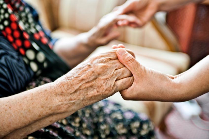 elderly ladys hands being held by younger person