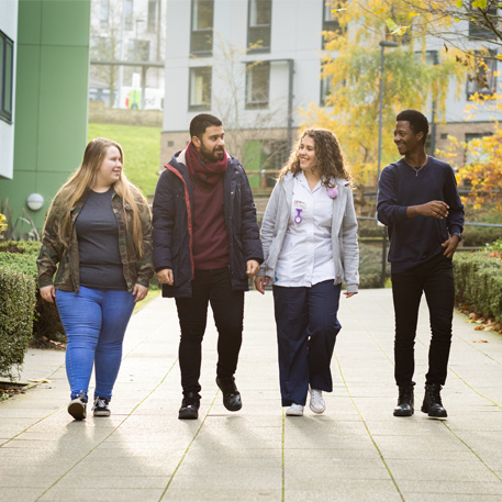 A group of four students walking around The Green accommodation exterior