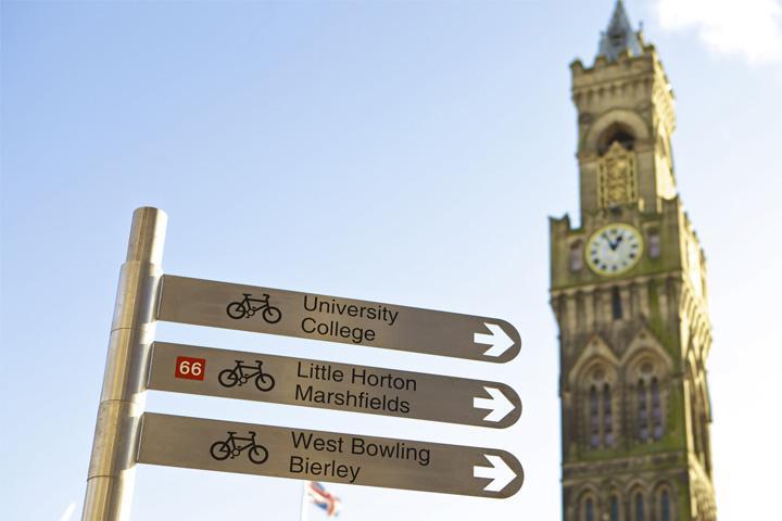 A signpost in front of Bradford City Hall directing cyclists towards University and College, Little Horton and Marshfields and West Bowling and Bierley