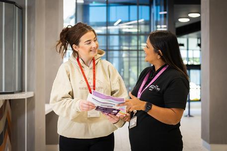A student talking to a member of support staff in the Richmond entrance