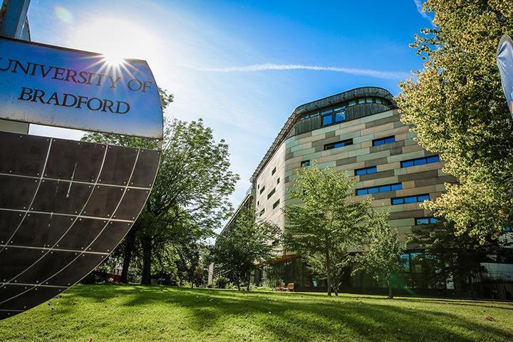 A large University of Bradford sign next to the Horton A Building on campus, on a sunny day.