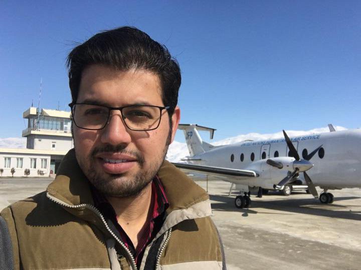 Headshot of Fahim stood in front of an airplane.