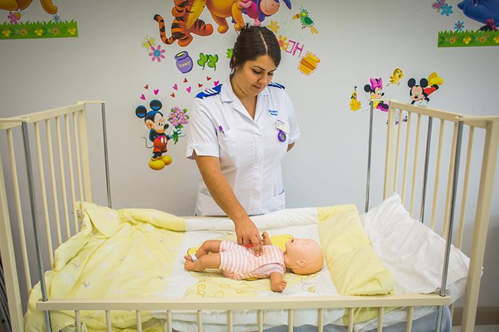 Student nurse, Rosie, practicing nursing techniques on a baby manekin