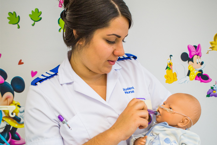 Student nurse, Rosie, feeding a baby mannequin medicine