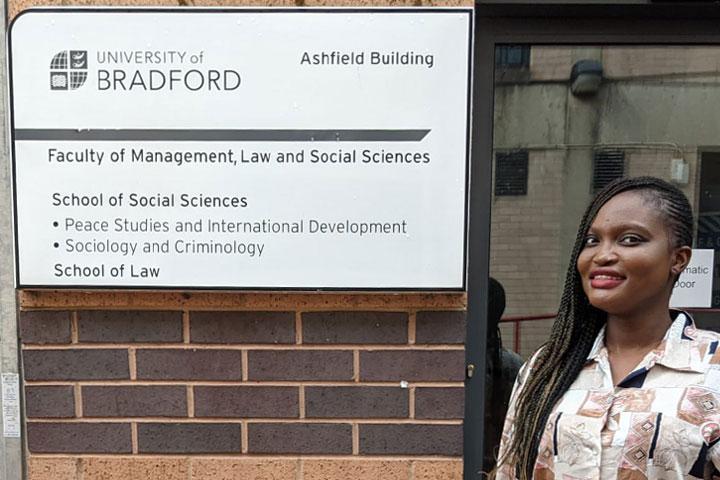 A person standing outside a building, next to a sign for the Ashfield Building at the University of Bradford.