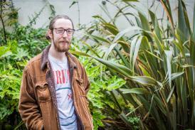 MA Filmmaking student  Sam Kane standing in front of some plants