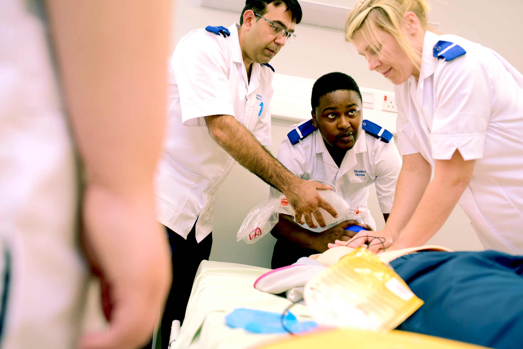 Three paramedic students resuscitating a practice manikin.