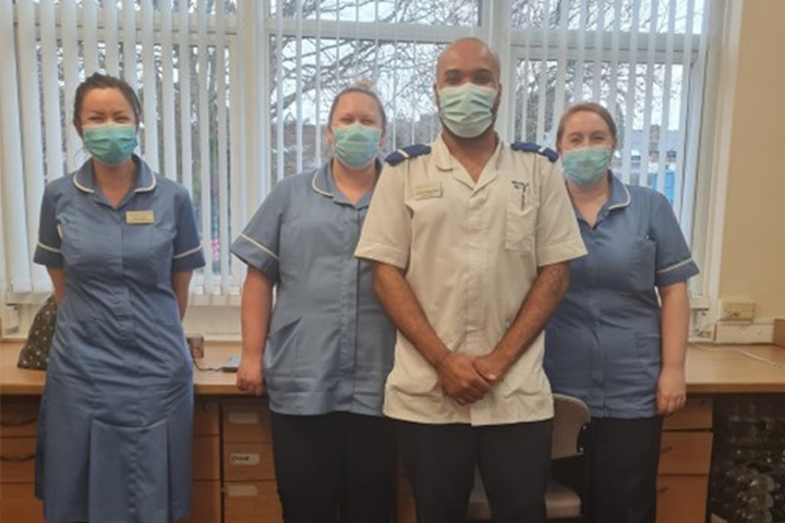 Aaron standing with colleagues on placement
