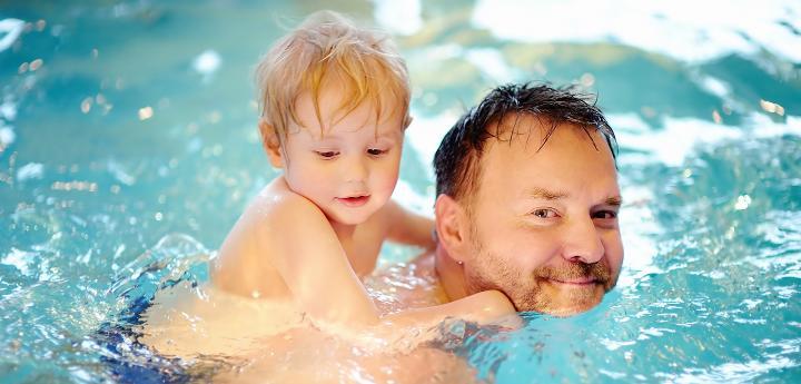 Father and son in swimming pool together smiling
