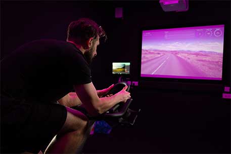 Man on spin bike watching virtual class