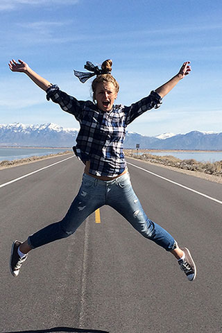 Student jumping from joy on empty road