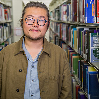 Chuanxin, an Accounting and Finance student, stood in the middle of two rows of bookshelves.